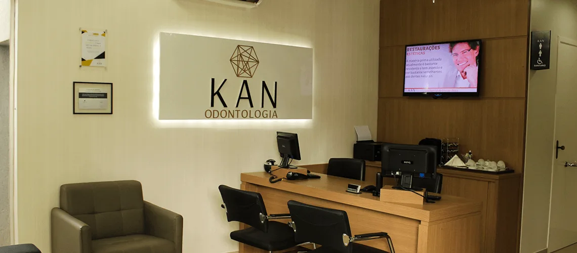 Recepção da KAN Odontologia com o logotipo iluminado na parede